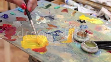 艺术家在调色板上混合油漆，艺术在调色板上刷混合油漆，艺术家在调色板上刷混合彩色油画。